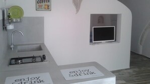 A modern kitchen with a sink, a green dish rack, a coffee sign, and a small TV. - La Maison Petite, Le Piccole Case Bianche (Ostuni)