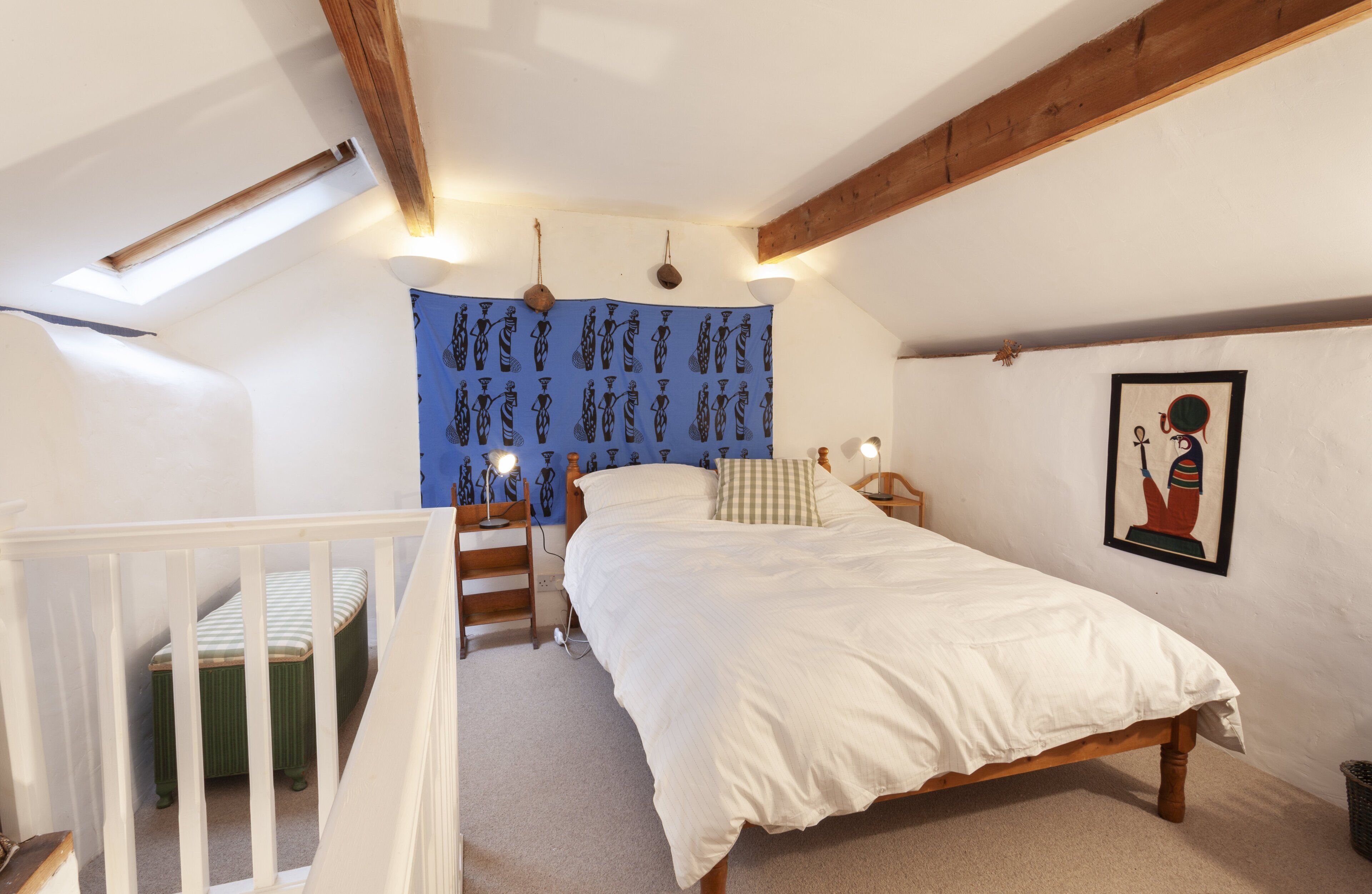 Ein Schlafzimmer mit einem Bett, einem Nachttisch, einer Lampe, einer Wandteppich und einem Gemälde.