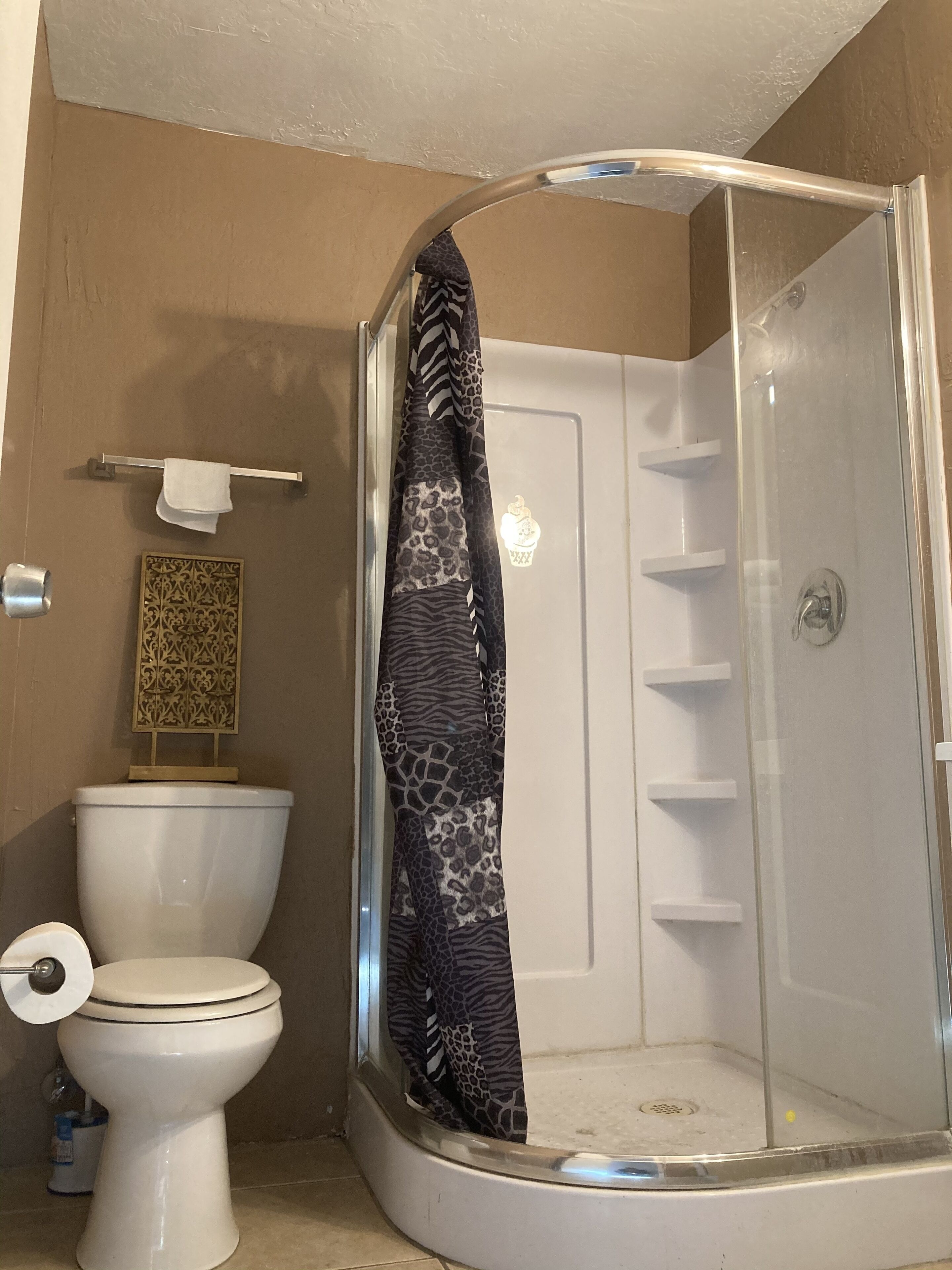 A bathroom with a shower, toilet, and towel rack.