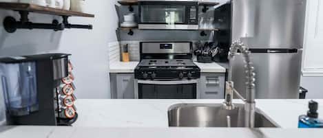 Une cuisine moderne avec des meubles blancs, un réfrigérateur en acier inoxydable, un four à micro-ondes et une cuisinière.