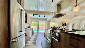 Uma cozinha moderna com eletrodomésticos de aço inoxidável, armários de madeira e vista para uma piscina.