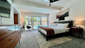 Quarto com cama, penteadeira, cadeira, mesa de cabeceira e ventoinha no teto.