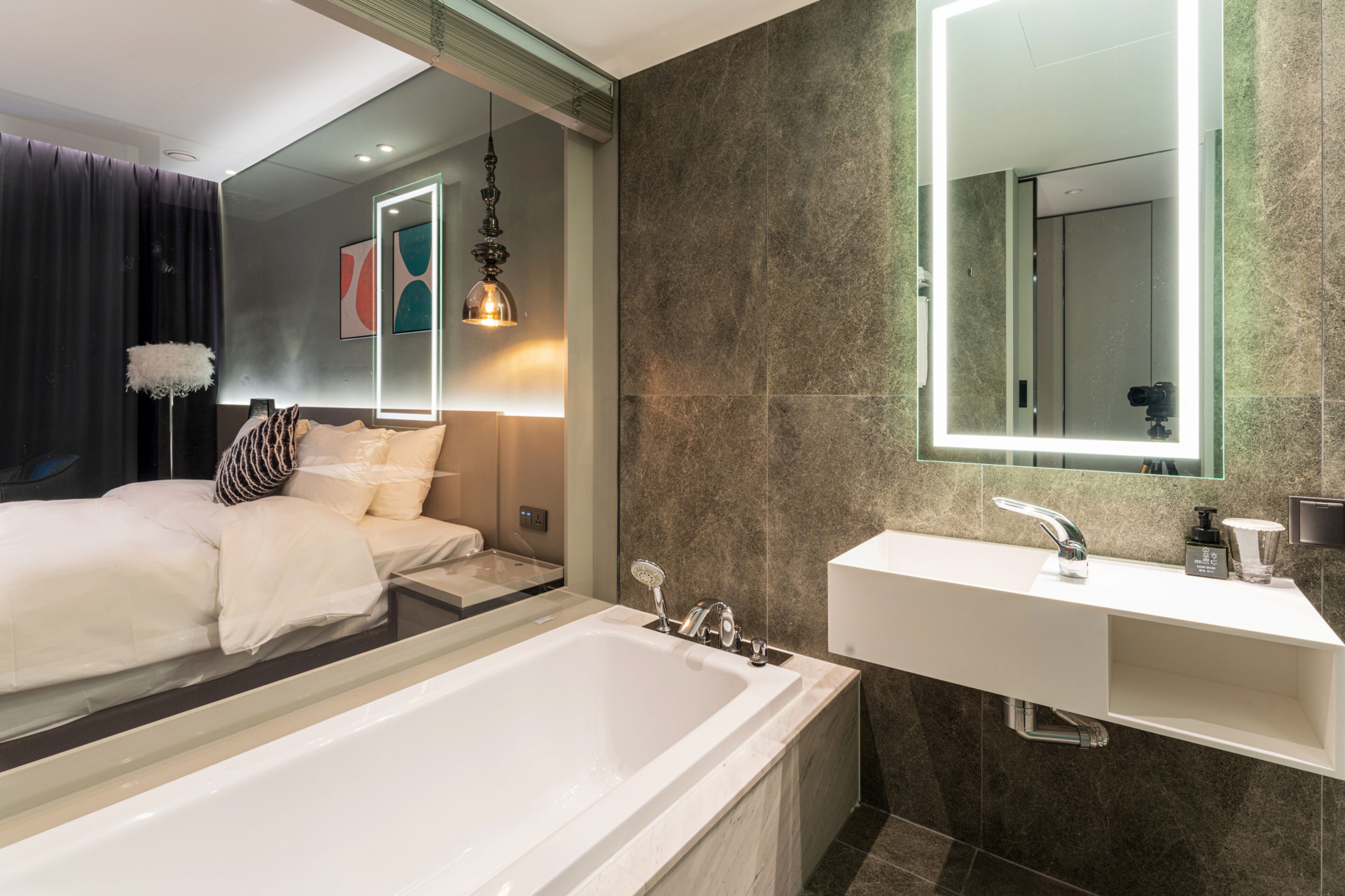 Un baño moderno con una bañera grande, un lavamanos blanco y un espejo sobre el lavamanos.