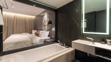 A modern bathroom with a large mirror, a bathtub, and a white sink.