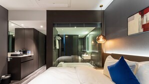 A modern hotel room with a large bed, a built-in desk, a glass shower enclosure, and a large mirror. - Hotel Soulhada (Incheon)