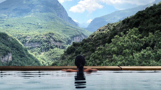 Eine Person in einem Schwimmbecken, im Hintergrund eine Berglandschaft.