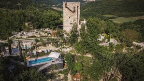 Eine Burg, umgeben von üppiger Vegetation, mit einem Schwimmbad und einem kleinen Boot.
