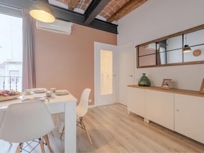 Een eethoek met een witte tafel, stoelen en een schaal fruit.