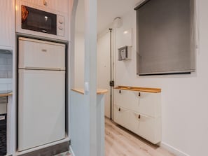 A compact kitchen with a built-in microwave, a refrigerator, and a wooden shelf. - Sants Montjuic Olympic View (Barcelona)