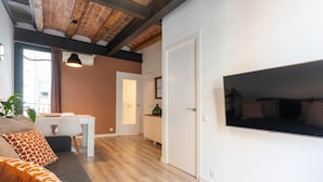 A modern living room with a sofa, a dining area, and a TV mounted on the wall. - Sants Montjuic Olympic View (Barcelona)