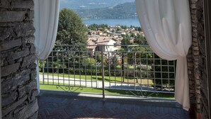 A balcony with a stone archway, white curtains, and a view of a lake and mountains. - VILLA NINFEA DEL LAGO (Baveno)
