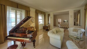 A spacious living room with a grand piano, a white sofa, and a glass coffee table. - VILLA NINFEA DEL LAGO (Baveno)