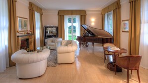 A spacious living room with a grand piano, comfortable seating, and a fireplace. - VILLA NINFEA DEL LAGO (Baveno)