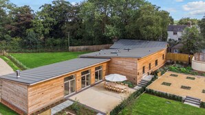 Une maison moderne en bois dotée d’une grande terrasse, d’une piscine et d’une pelouse bien entretenue.