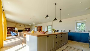 Une cuisine spacieuse dotée d’un grand îlot central, de luminaires suspendus et offrant une vue sur l’extérieur.