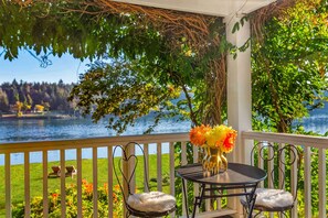 A balcony with a table and chairs, overlooking a lake and greenery. - 'The Hammersley' Luxury Waterfront Estate! (Shelton)