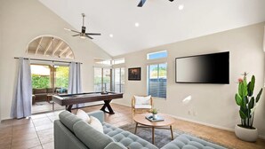 A spacious living room with a pool table, comfortable seating, and a large TV.