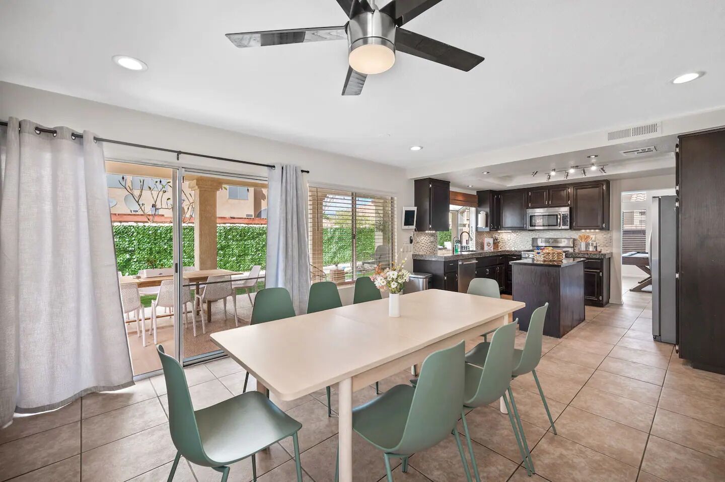 A modern kitchen with dark cabinets, a central island, and a dining area with a table and chairs.
