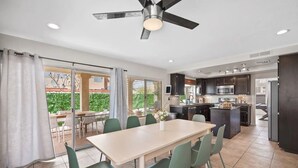 A modern kitchen with dark cabinets, a central island, and a dining area with a table and chairs.