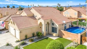 A residential property with a swimming pool, a well-maintained lawn, and a clear view of the surrounding neighborhood.