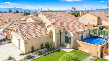 A residential property with a swimming pool, a well-maintained lawn, and a clear view of the surrounding neighborhood.