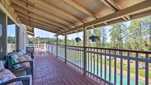 A covered wooden deck with wicker furniture and hanging planters. - Jackson Escape w/ Hot Tub & Mtn Views! (Jackson)