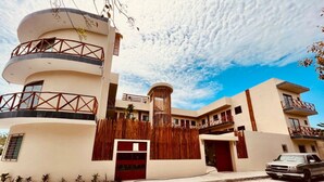 A modern hotel with a curved facade, multiple balconies, and a central cylindrical tower. - Hotel Manglar Suites (Mahahual)