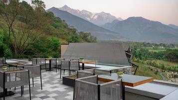 Terraza exterior con mobiliario de mimbre y vistas a montañas.