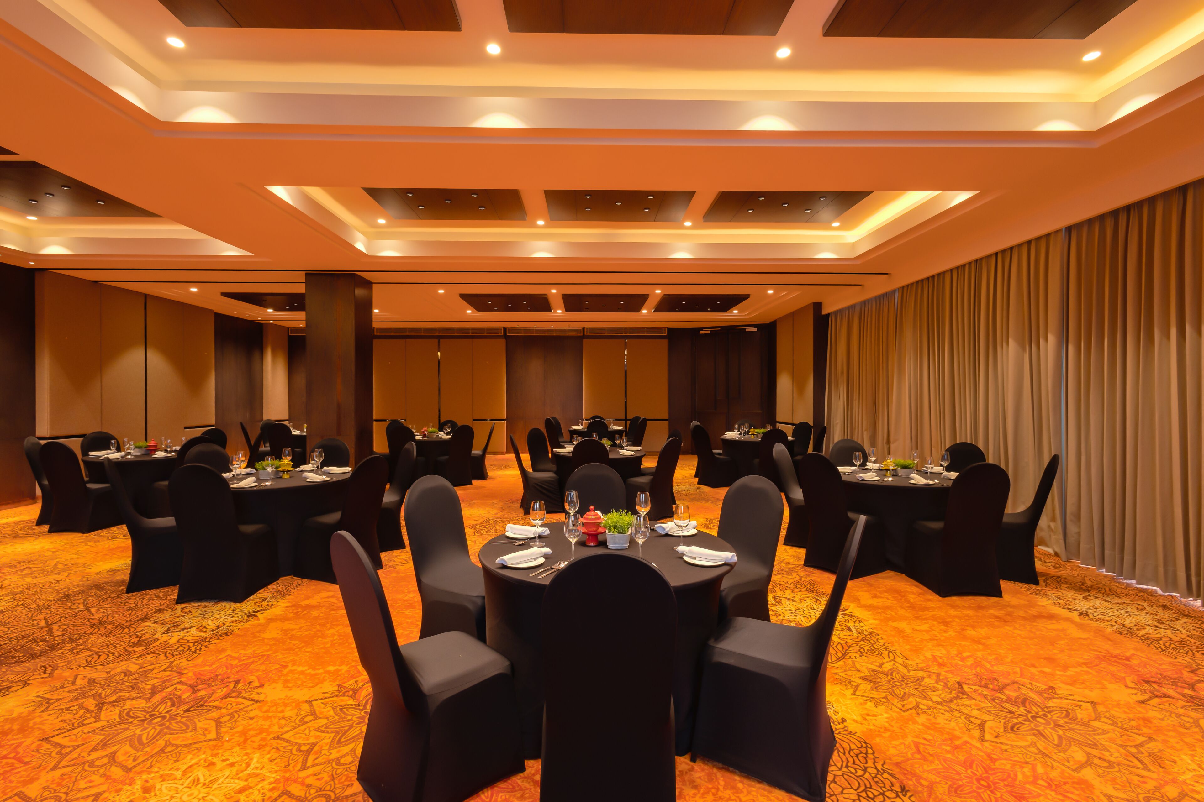 A conference room with round tables, black chairs, and a carpeted floor.