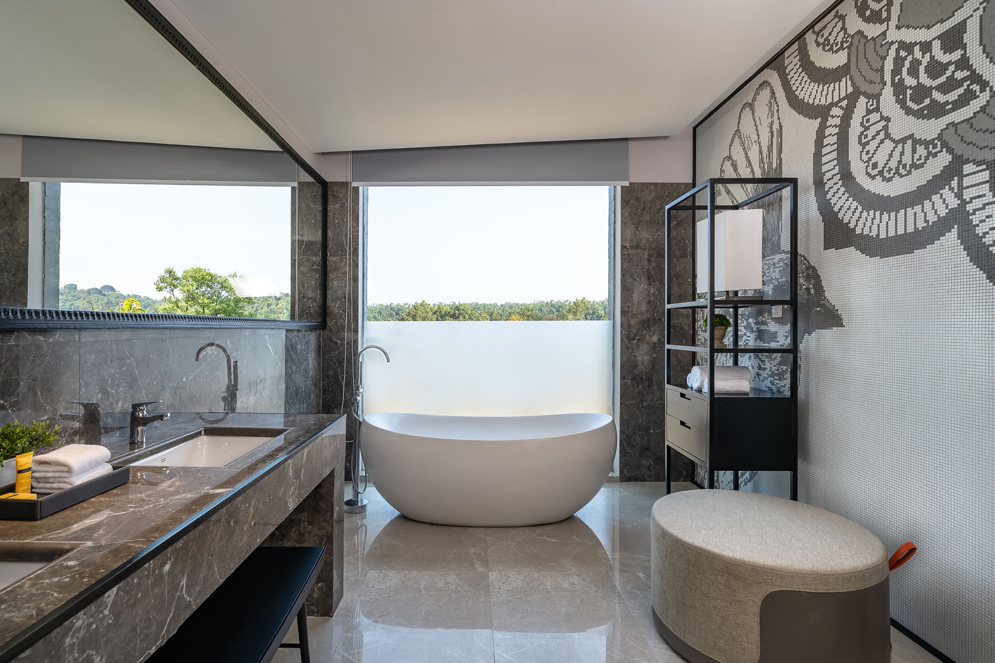 A modern bathroom with a freestanding bathtub, a large mirror, and a view of greenery through a large window.