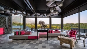 A modern interior with a large window, a sofa set, a table, and a dog. - Norbu The Montanna, Dharamshala - IHCL SeleQtions (Dharamshala)