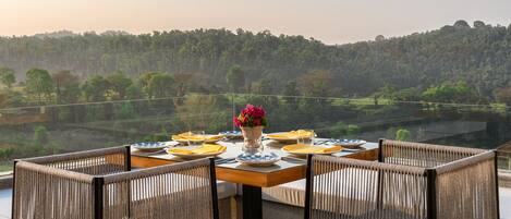 Une table dressée pour quatre personnes, entourée de chaises en osier, avec vue sur un paysage magnifique.