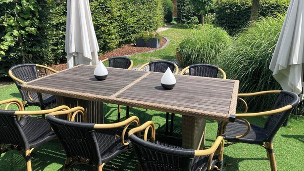An outdoor patio with a rectangular table and eight wicker chairs.