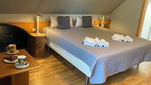 A hotel room with a bed, bedside tables, a chair, a coffee table, and a window.