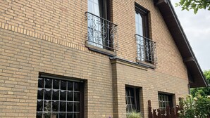 A two-story brick building with large windows and decorative iron railings on the balconies.