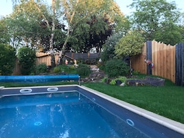 Una piscina con terraza de madera y valla de madera al fondo.