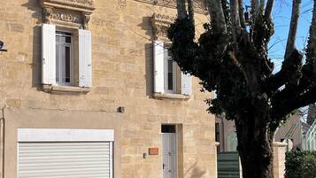 A stone building with two windows, a garage door, and a tree in front.