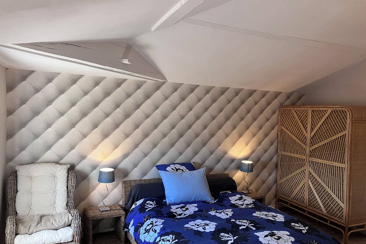 A bedroom with a bed, a chair, a nightstand, and a wardrobe.