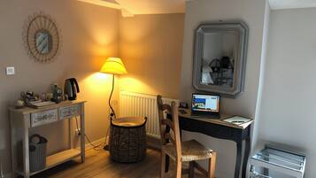 Une petite pièce comprenant un bureau, une chaise, une lampe et un ordinateur portable.