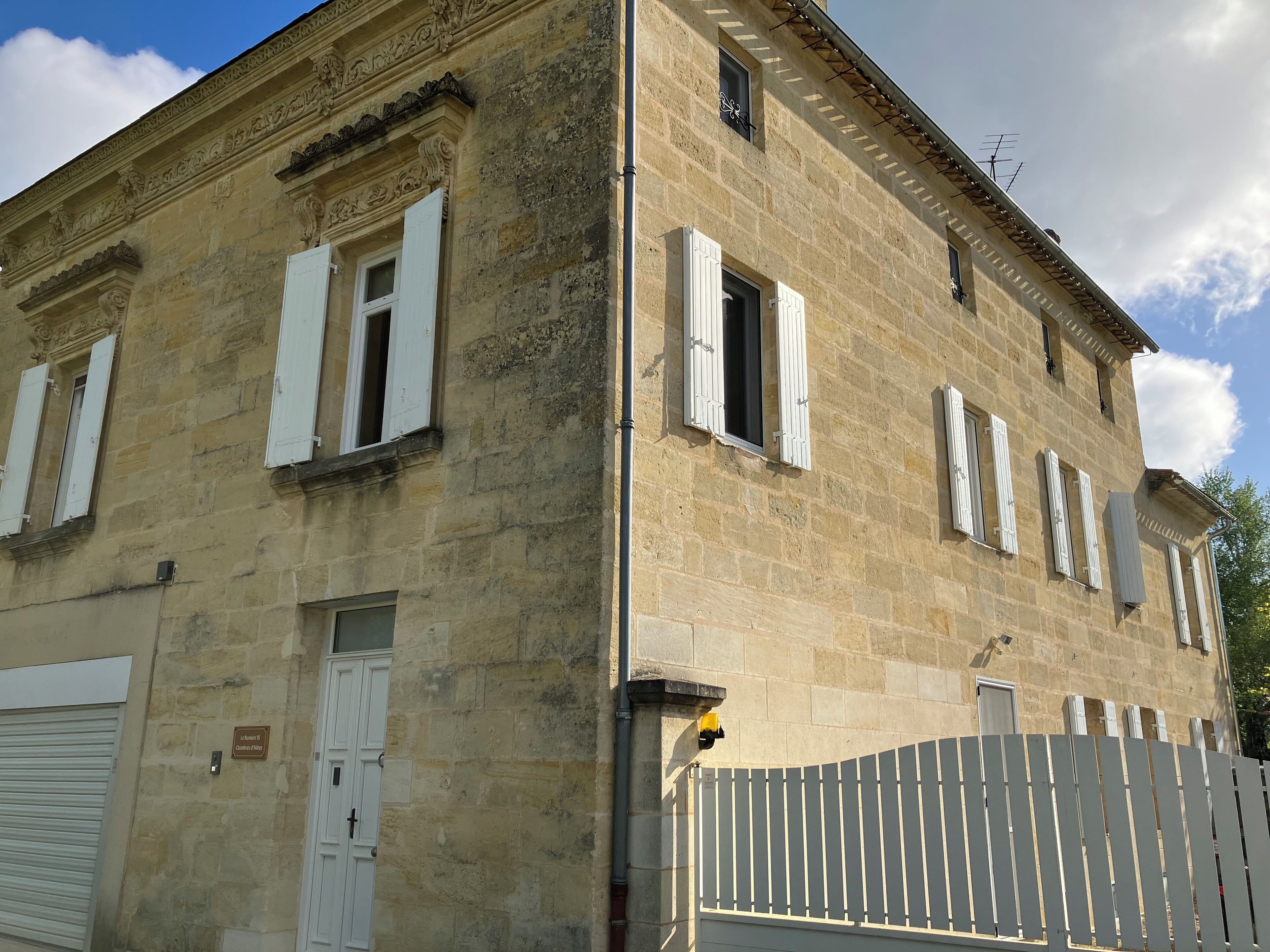 Un edificio de piedra con varias ventanas, una puerta de garaje y un acceso portón cerrado.