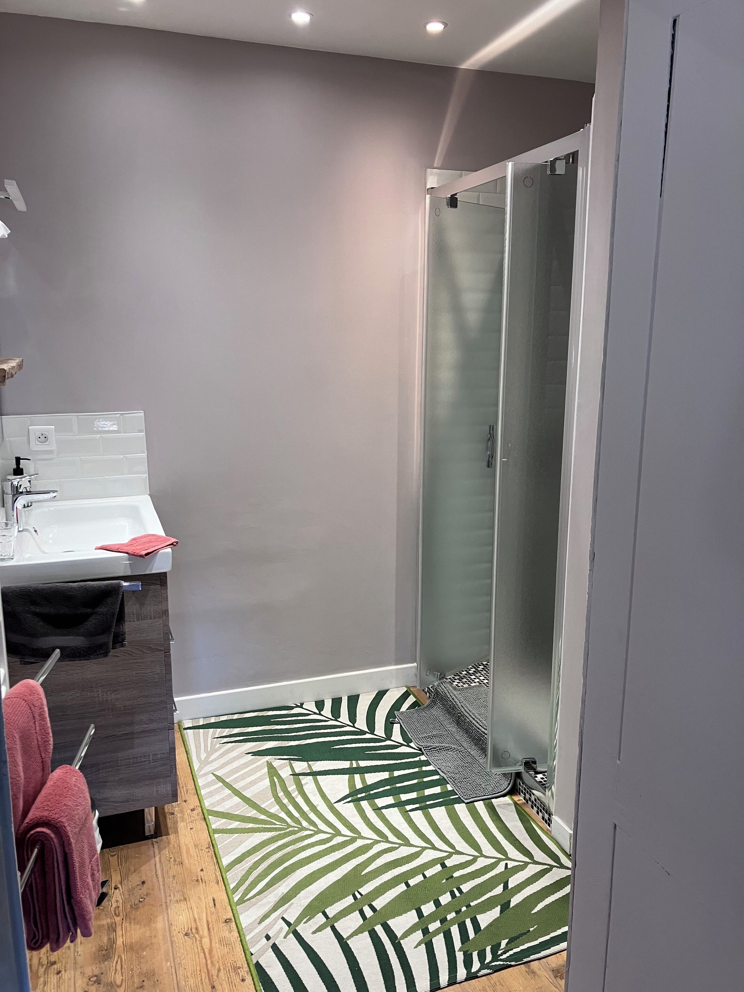 Un baño moderno con ducha, lavamanos y espejo.