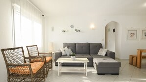 A living room with wicker furniture, a grey sofa, a white coffee table, and a small wooden table. - A90 EDIFICIO IFACH III 7º 36 (Calpe / Calp)