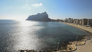 A coastal view with a rocky shoreline, a beach, and a cityscape in the background. - A90 EDIFICIO IFACH III 7º 36 (Calpe / Calp)
