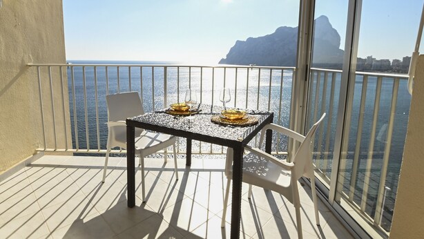 A balcony with a table and chairs, overlooking a body of water and a mountainous landscape. - A90 EDIFICIO IFACH III 7º 36 (Calpe / Calp)