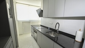 A modern kitchen with a black countertop, stainless steel sink, and white cabinets. - A90 EDIFICIO IFACH III 7º 36 (Calpe / Calp)