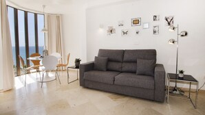 A modern living room with a grey sofa, a round dining table with chairs, a floor lamp, and artwork on the wall. - A85 EDIFICIO OCEANIC 304 (Calpe)