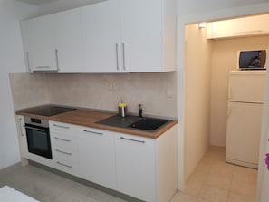 Eine moderne Küche mit weißen Schränken, einer Holz Arbeitsplatte, einem eingebauten Backofen und einem Kühlschrank.