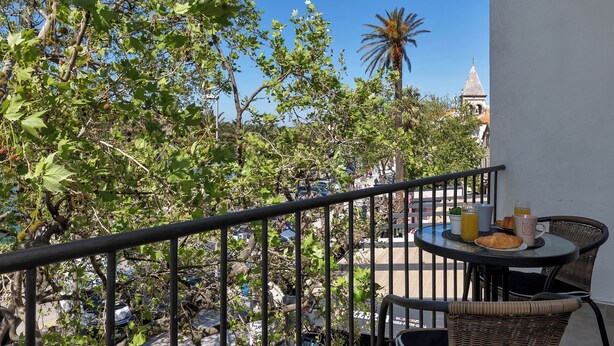 A balcony with a table set for breakfast, including croissants, juice, and coffee. - Apartment Riva ,city center (Makarska)