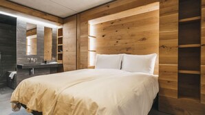 Un dormitorio moderno con cabecera de madera, una cama grande, tocador empotrado y un espejo.