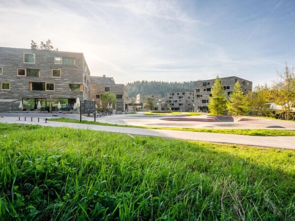 A modern building complex with multiple residential units, a central courtyard, and surrounding greenery. - Cosy Alpine by Interhome (Laax)